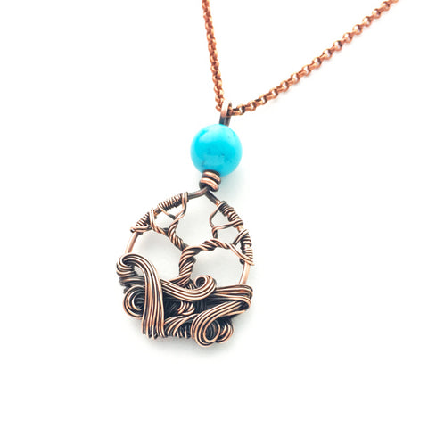 mini copper tree necklace with turquoise colored bead and decorative swirls.